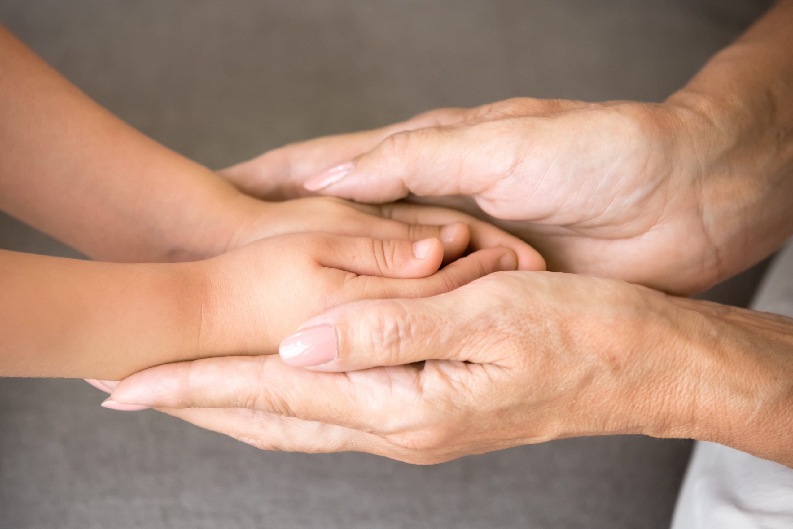 Elderly person holding a child’s hands, symbolising care and guardianship.