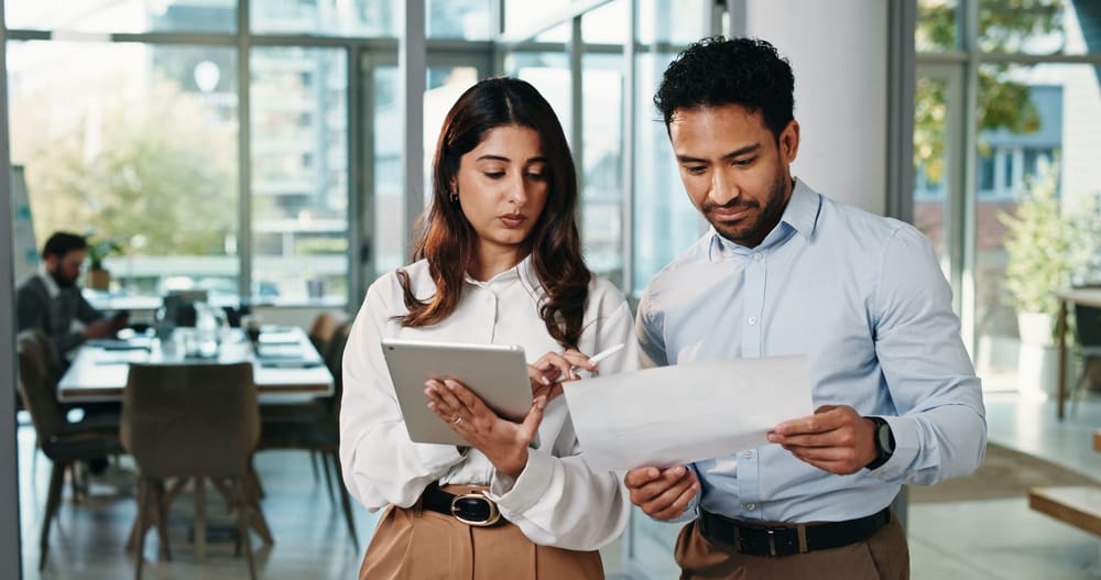 Two professionals reviewing payroll and HR documents in an office, reflecting upcoming statutory rate changes and employment law updates for April 2026.